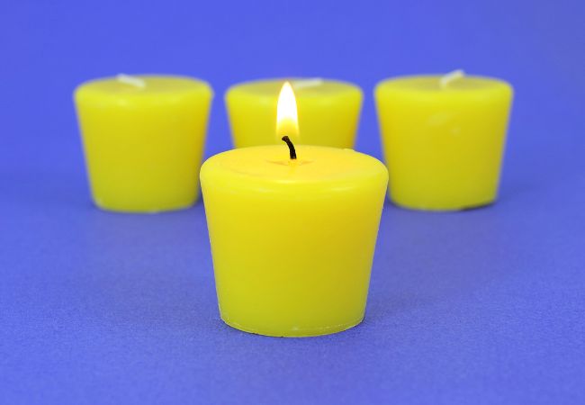 burning citronella candle with three ones unlit in a blue background.