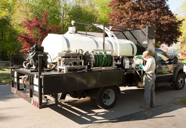 A Regal Tree PHC truck with an arborist preparing pgr solution to treat some trees on a property near Massachusetts.